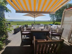 einen Tisch und Stühle mit Sonnenschirm auf einer Terrasse in der Unterkunft Cosy holiday home on Lake Veere with the beach right at your doorstep in Kamperland