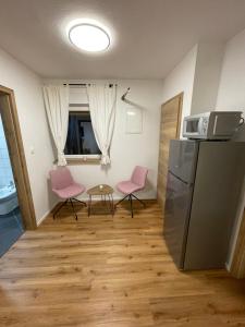 eine Küche mit 2 rosa Stühlen und einem Kühlschrank in der Unterkunft Apartma Guide 360 in Bovec