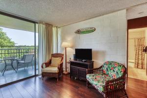 a living room with a tv and a couch and a chair at Maunaloa Shores 612 in Hilo
