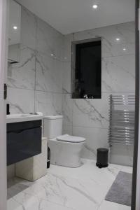 a white bathroom with a toilet and a sink at 5 star Apartment in London
