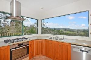 uma cozinha com um lavatório e 2 janelas grandes em Peaceful and close to town em Whangarei