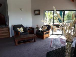 een woonkamer met 2 stoelen en een tafel bij Peaceful and close to town in Whangarei