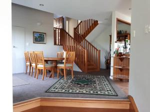 een eetkamer met een tafel en een trap bij Peaceful and close to town in Whangarei