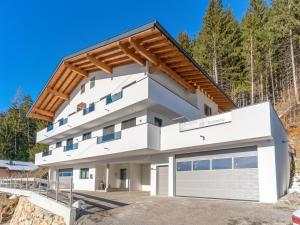 uma casa branca com um telhado de madeira e uma garagem em Bergliebe Apartments em Gerlosberg