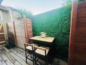 a table and chairs on a patio with a green hedge at Fab lil home Central to all NOLA / near City Park in New Orleans