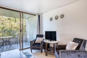 a living room with chairs and a tv and a balcony at Maunaloa Shores 109 in Hilo