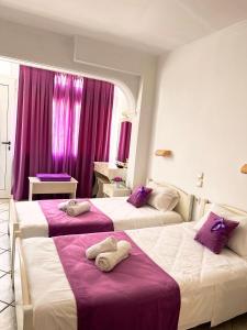 two beds in a hotel room with purple curtains at Apart Hotel Blumarin in Agios Gordios