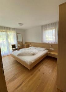 - une chambre avec un grand lit et du parquet dans l'établissement Apartments Stoll, à Valle Di Casies