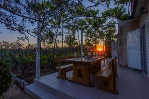 une table en bois et des bancs sur une terrasse avec vue sur le coucher du soleil dans l'établissement Holiday house Olive Tree, à Kaočine