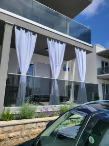 a car parked in front of a building with white curtains at Studio apartman Pegi in Šimuni