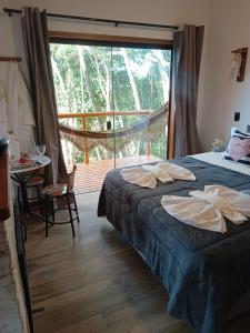 a bedroom with a bed and a table and a large window at Mountain House Hospedagem in Monte Verde