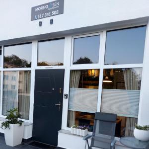 ein Gebäude mit einer schwarzen Tür und einem Stuhl davor in der Unterkunft Apartament typu studio Morski Sen-centrum in Mielno