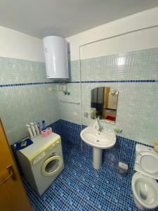 Baño de azulejos azules con aseo y lavamanos en Like my home apartment, en Durrës