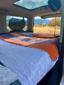 a bed in the back of a van with a blanket at Go Camp Maui in Ah Fong Village