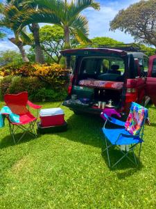 two chairs and a car parked in the grass at Go Camp Maui in Ah Fong Village