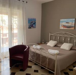 Cas'Ilenia Lido Azzurro في بورتو إمبيدوكلي: غرفة نوم بها سرير وكرسي ونافذة