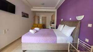 a bedroom with a large bed with purple walls at Valeriana Studios in Parga