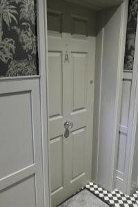 a white door in a room with a checkered floor at York House Hotel in Whitley Bay