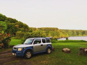 une jeep bleue et argentée garée dans un champ dans l'établissement Go Camp Maui, à Ah Fong Village