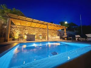 a swimming pool in front of a stone building with a pergola at Euphoria Tinos Suite in Skaládhos