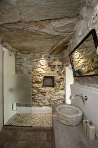 a stone bathroom with a toilet and a stone wall at Euphoria Tinos Suite in Skaládhos