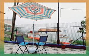 two chairs and an umbrella in front of a fence at Cabaña mirador bremen in Filandia +1 photo