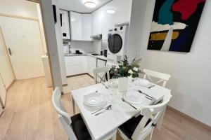 a white dining room table with white chairs and a kitchen at Very quiet apartment with balcony in Saint-Denis