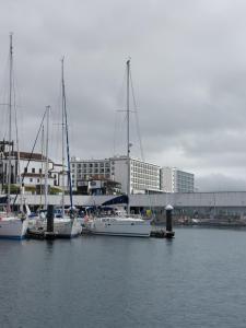 un grupo de barcos atracados en un puerto con una ciudad en Galeao Tropical Unipessoal Limitada, en Ponta Delgada