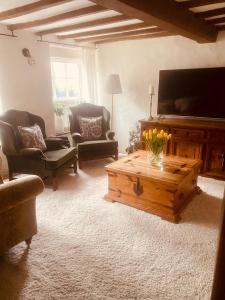 a living room with a tv and a wooden coffee table at Mansfield Cottage in Kilsby