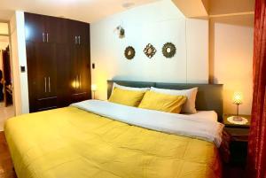 1 dormitorio con 1 cama grande con sábanas amarillas en Cusco Mágico 1 - Aparthotel Condominio Las Torres Kayser I, en Cusco
