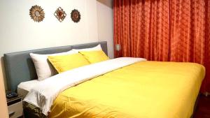 1 dormitorio con 1 cama con sábanas y almohadas amarillas en Cusco Mágico 1 - Aparthotel Condominio Las Torres Kayser I, en Cusco
