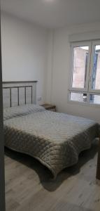 a bed in a white room with a window at Apartamento BELA VISTA in Sanxenxo