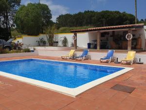 a swimming pool with chairs and a house at Sondela Self Catering in São Martinho do Porto