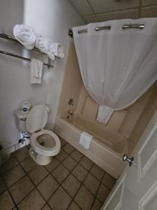 een badkamer met een toilet en een bad met handdoeken bij Platte Valley Inn in Columbus