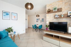 ein Wohnzimmer mit einem blauen Sofa und einem Flachbild-TV in der Unterkunft Apartman Jelena in Vrbnik