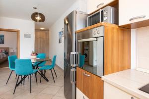 eine Küche mit einem Kühlschrank und einem Tisch mit blauen Stühlen in der Unterkunft Apartman Jelena in Vrbnik