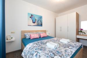 Schlafzimmer mit einem Bett mit blauen und rosa Kissen in der Unterkunft Apartman Jelena in Vrbnik