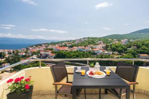 a table with a plate of food on a balcony at Apartman Jelena in Vrbnik