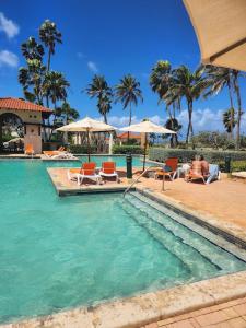 - une piscine avec des chaises et des parasols dans un complexe dans l'établissement Tierra Del Sol...OCEAN FRONT GOLF AND TENNIS RESORT CONDO, à Palm-Eagle Beach