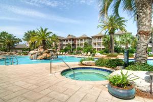 a resort pool with a hot tub and palm trees at Bliss Getaway in Destin