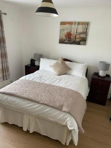 a bedroom with a bed with white sheets and pillows at Large Townhouse with Gardens in Kingscourt