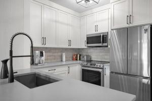 a kitchen with white cabinets and a stainless steel refrigerator at Beautiful Renovated Wolf 2Bed 2Bath in Canmore