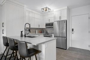 a kitchen with white cabinets and a kitchen island with chairs at Beautiful Renovated Wolf 2Bed 2Bath in Canmore