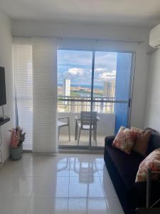 een woonkamer met een bank en uitzicht op een balkon bij Apartamento Cerca al mar in Cartagena
