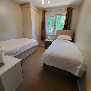 1 dormitorio con 2 camas y ventana en Aviemore Bungalow, Dalfaber en Aviemore