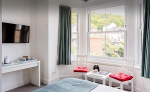 a bedroom with a bed and two chairs and a window at Brackenbury House in Portland