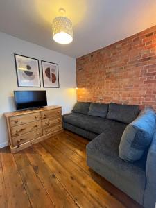 a living room with a couch and a brick wall at Red Brick House in Yeovil