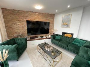uma sala de estar com sofás verdes e uma televisão de ecrã plano em Luxurious Panorama House with Pool and Sauna em Budaörs