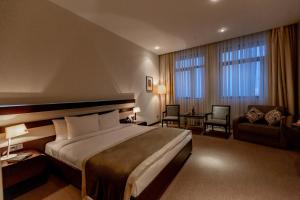 um quarto de hotel com uma cama grande e uma cadeira em Zirve Hotel em Shahdag
