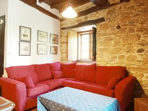 a red couch in a room with a stone wall at Corredoira in Viveiro